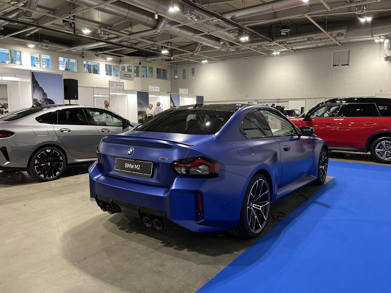 Rear view of matte blue coupe with quad exhaust and sporty wheels