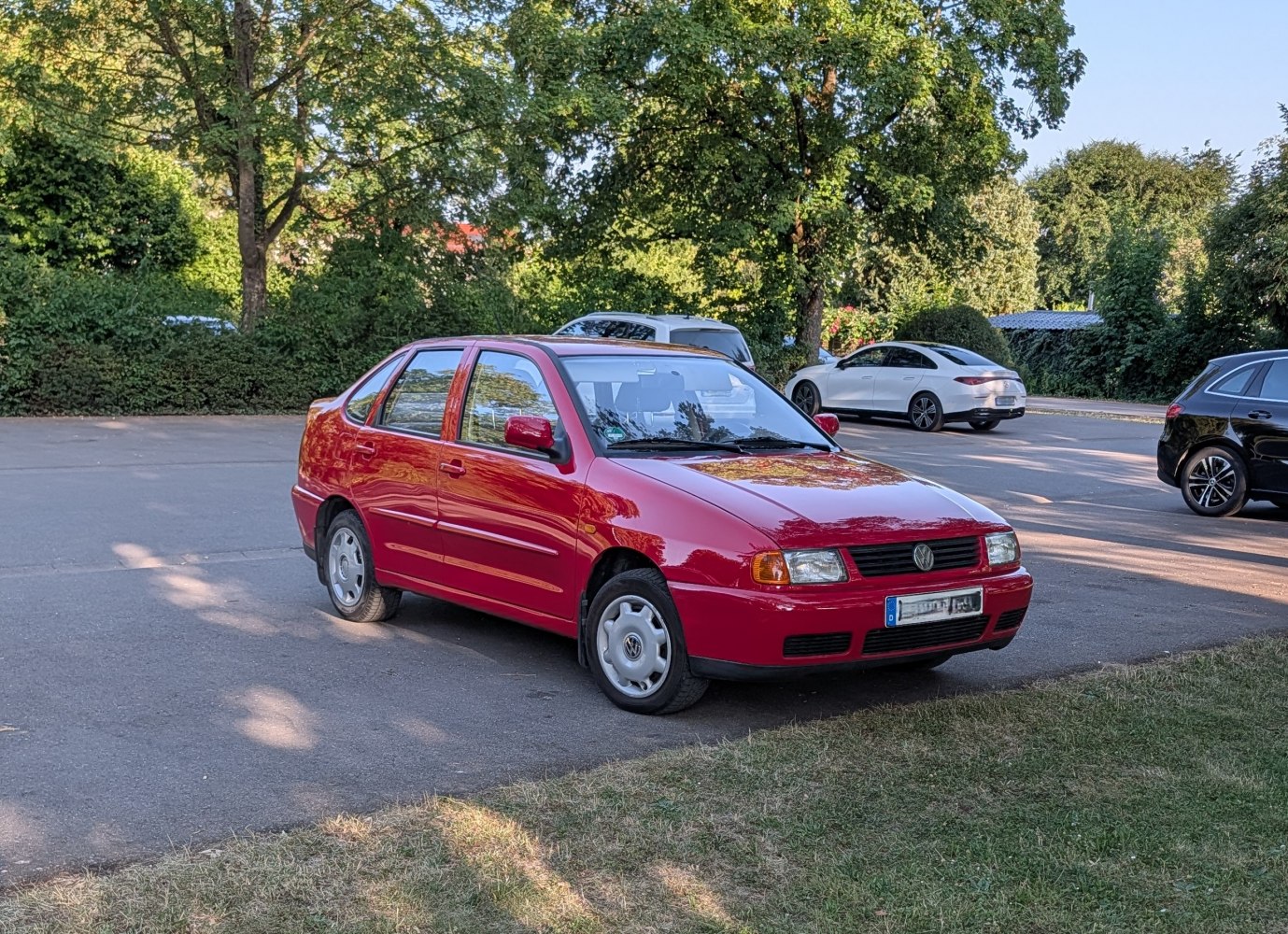 Red sedan with front-side view and classic compact design in urban parking.