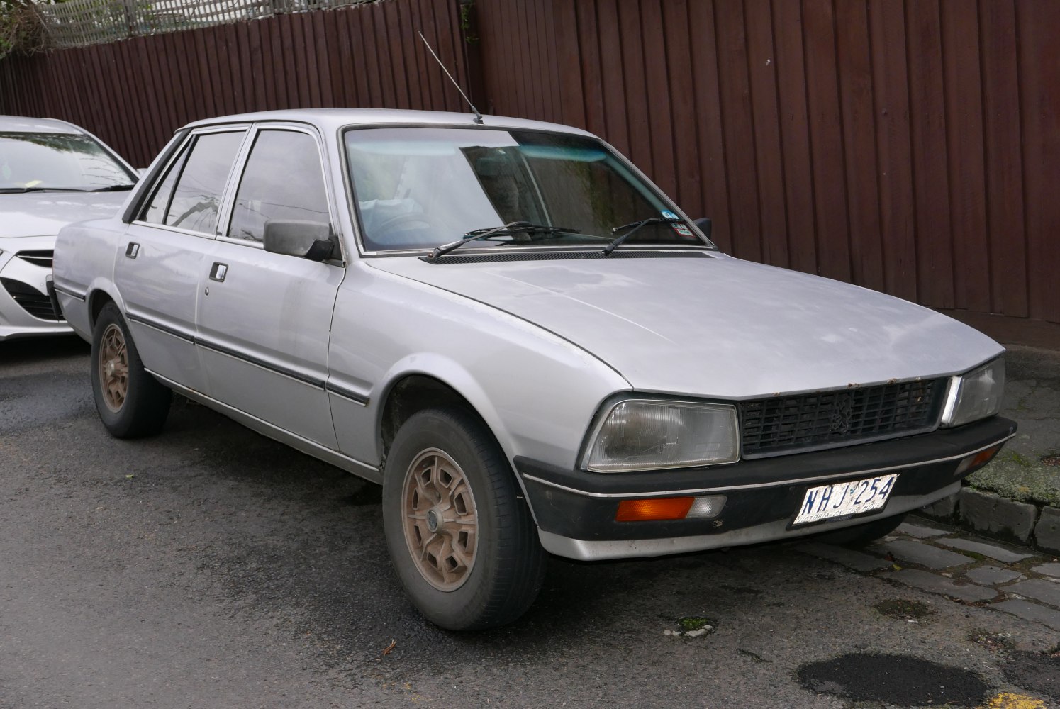 Front and side view of a vintage Peugeot sedan with classic headlights and grille.