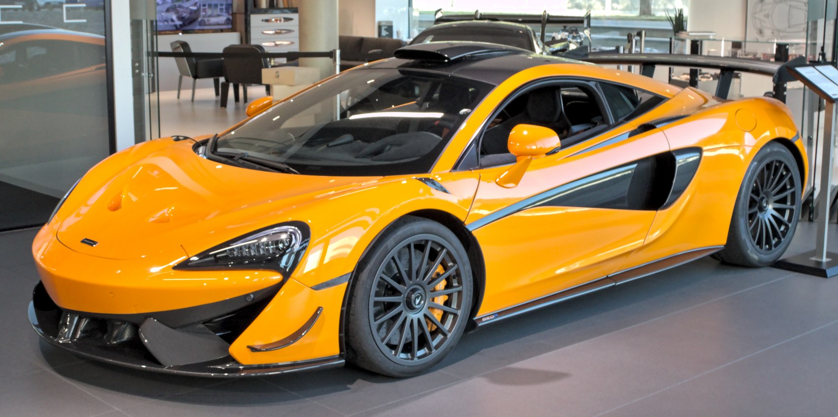 Orange sports car with aerodynamic front and rear wing, black multi-spoke wheels
