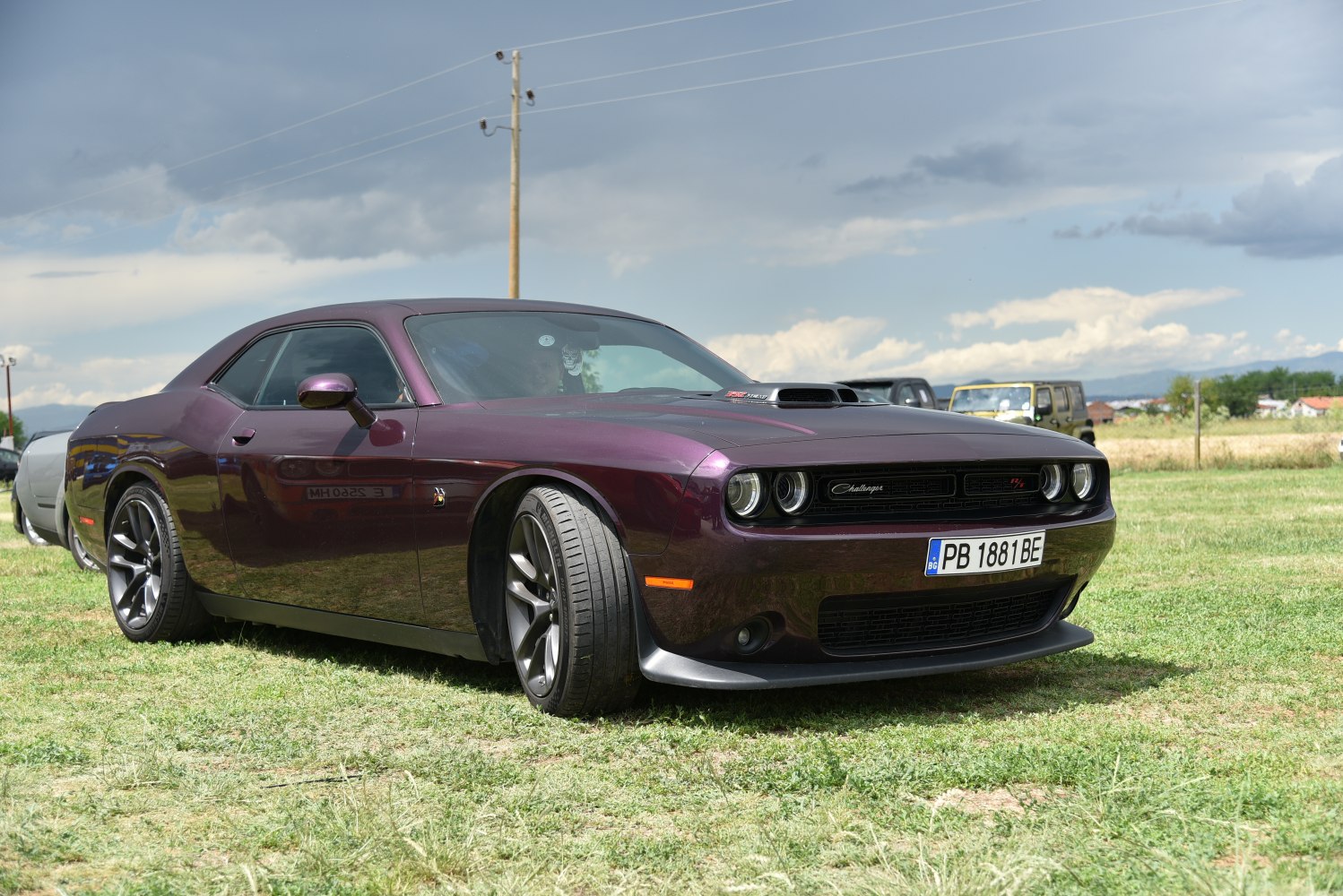 Muscle car front-side view with hood scoop and sporty wheels