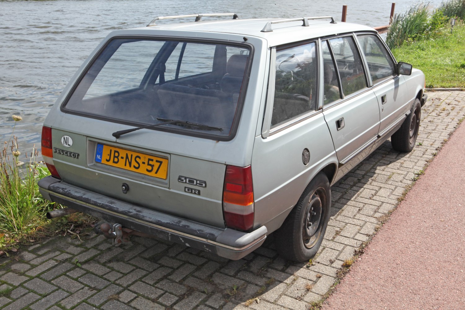 Rear and side view of a boxy station wagon with roof rack and tow hitch