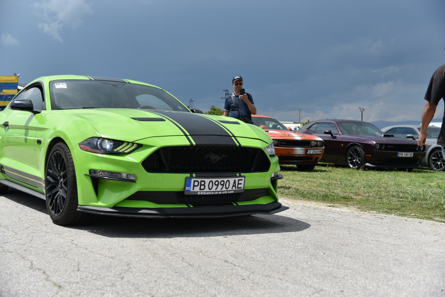 Front view of bright green sports car with black racing stripes and aggressive headlights