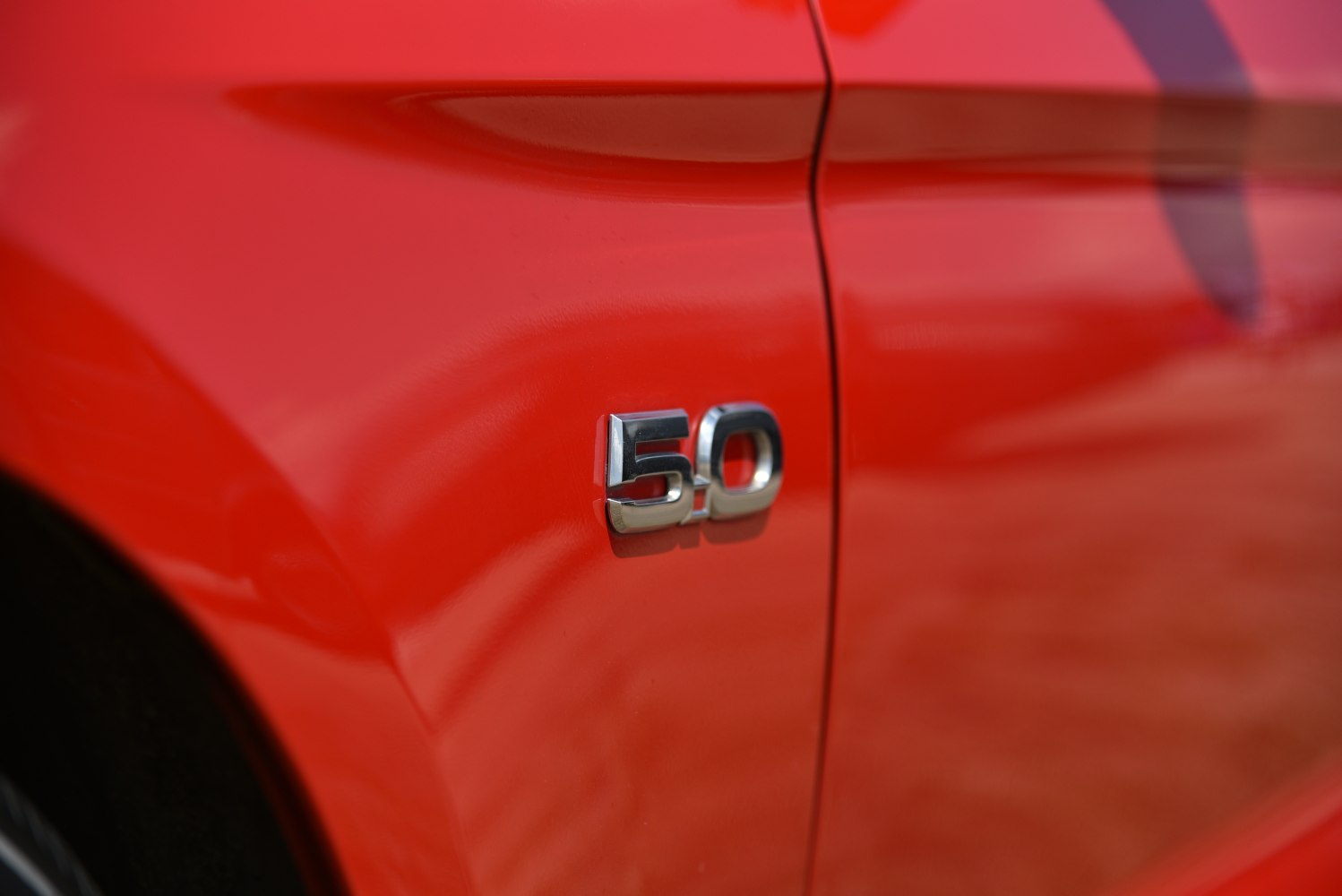 Close-up of 5.0 chrome badge on red muscle car fender