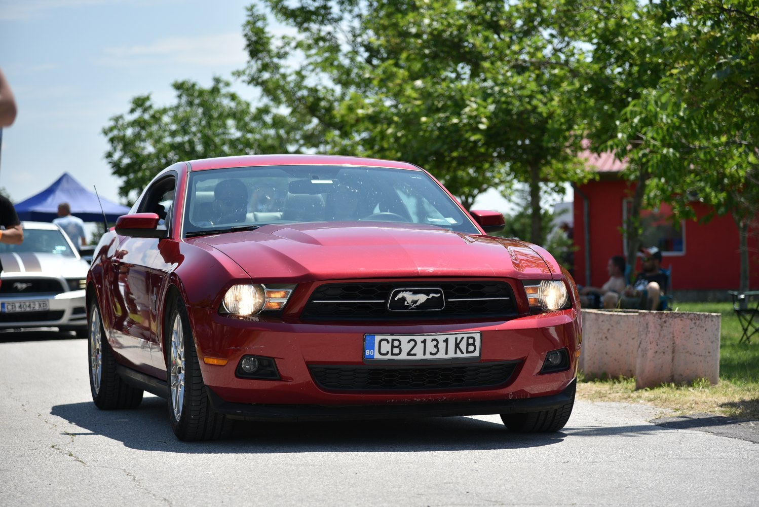 Front view of a red muscle car with headlights on and distinct grille