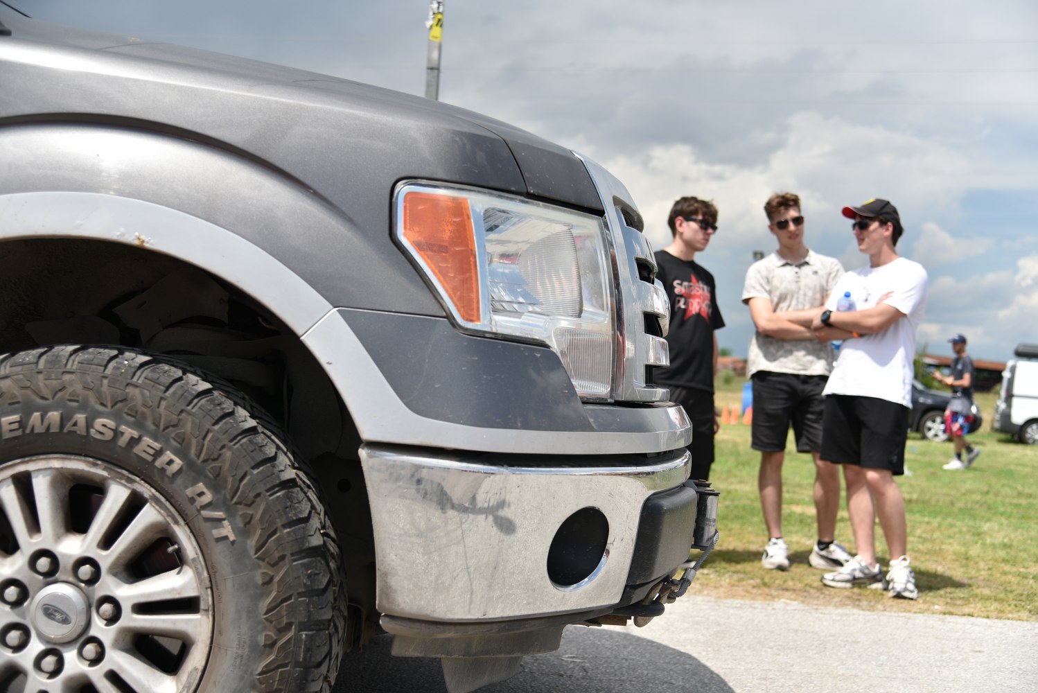 Close-up of truck front grille, headlight, and rugged off-road tire tread