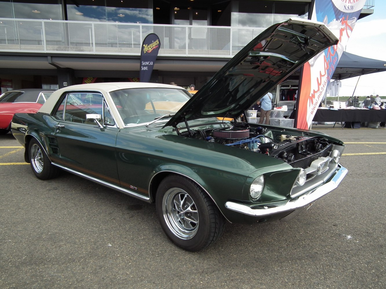 Dark green convertible with white soft top and open hood showing engine