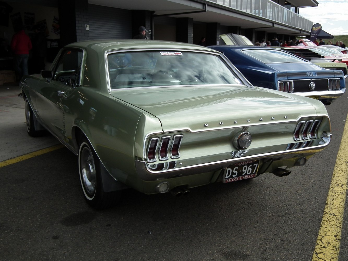 Rear view of a classic Mustang with distinctive triple vertical taillights and chrome bumper