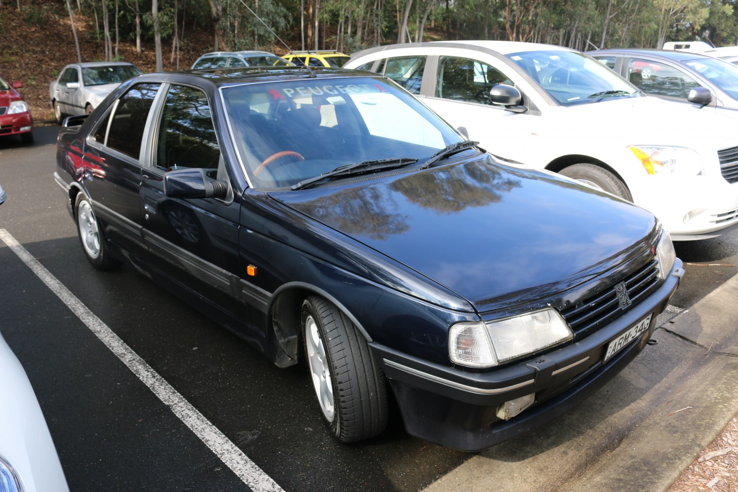 Side and front end view of a 1990s sedan with clear headlights and alloy wheels