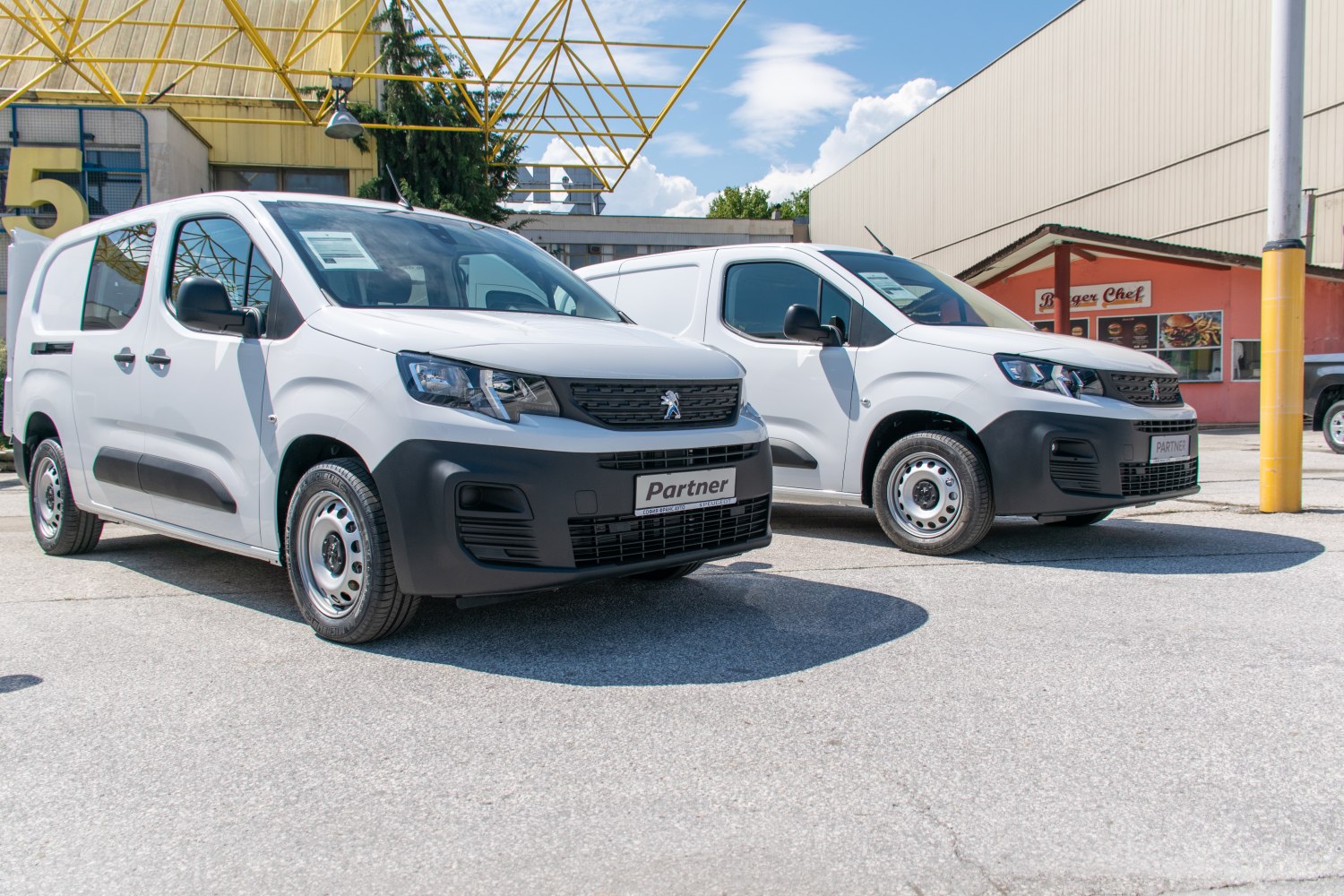 Two white commercial vans with sliding side doors and robust front bumpers