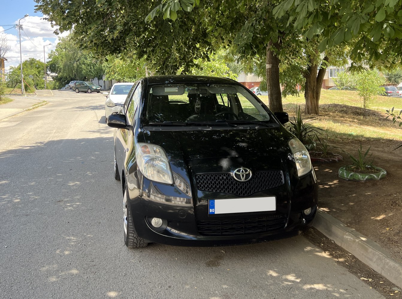 Front view of black compact 3-door hatchback with clear headlights and grille.
