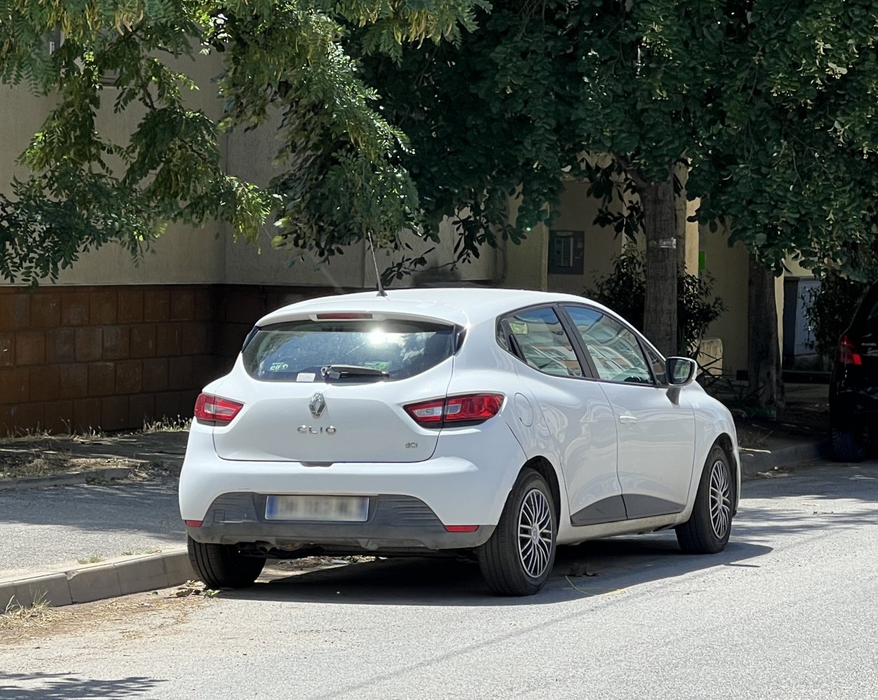 Rear and side view of a white hatchback car parked.