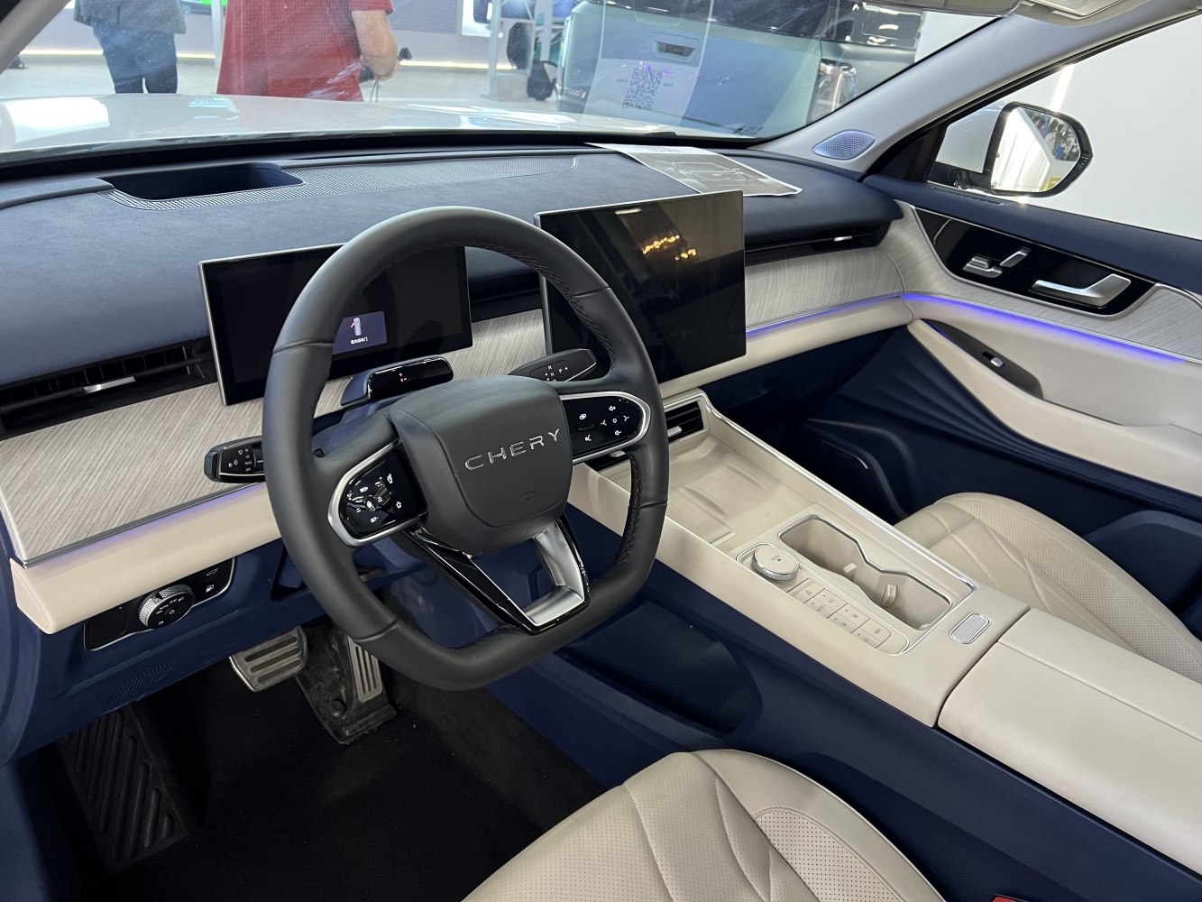 Dual digital screens, modern steering wheel, and luxury ambient lighting.