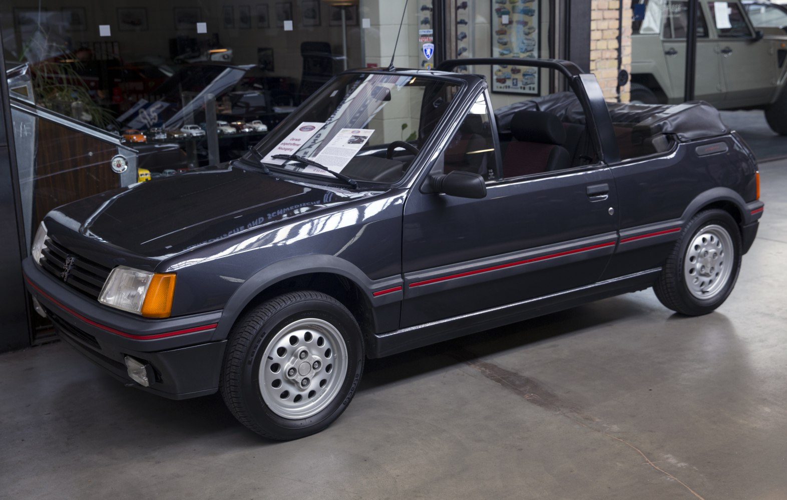 Convertible car with red side stripe and alloy wheels.