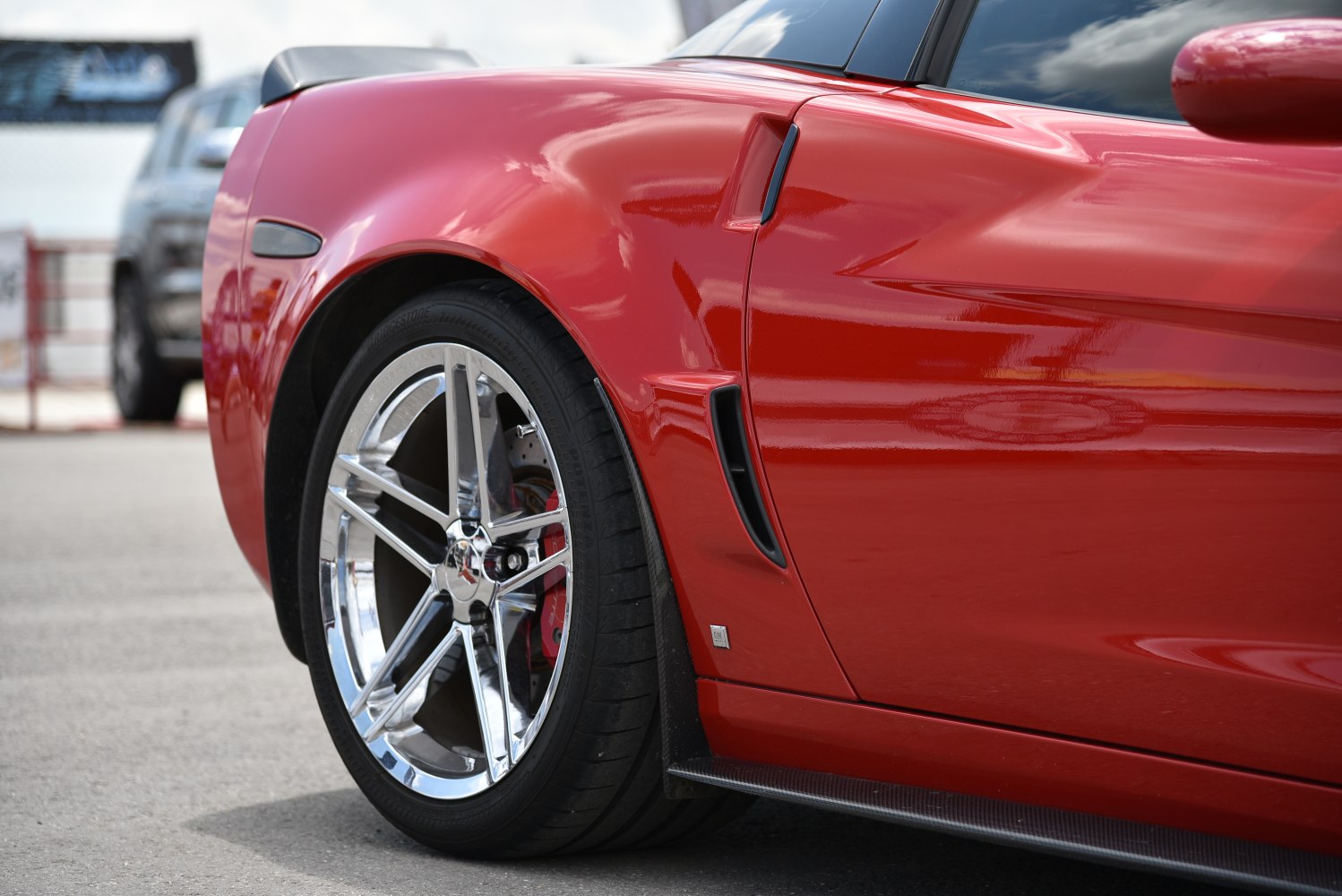 Close-up of shiny chrome wheel and side vent on red sports car