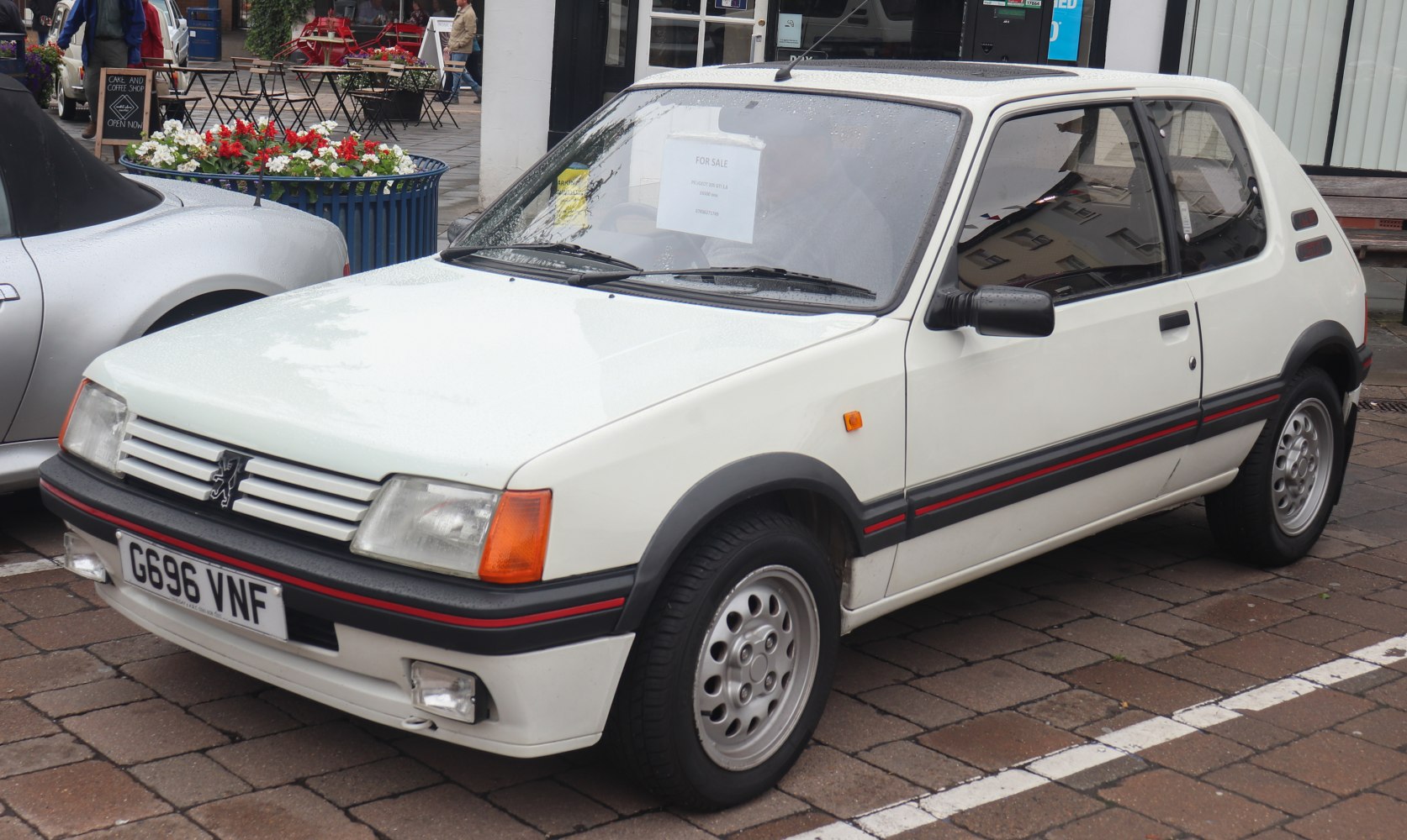 White 3-door hatchback with red stripe trim and alloy wheels