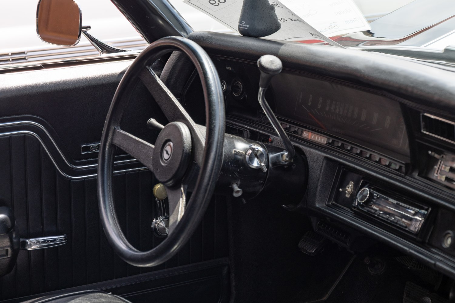Classic steering wheel and dashboard with manual gearshift in vintage 1970s car