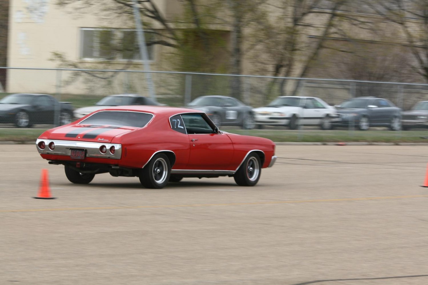 Rear view of classic red muscle coupe with racing stripes and round tail lights.