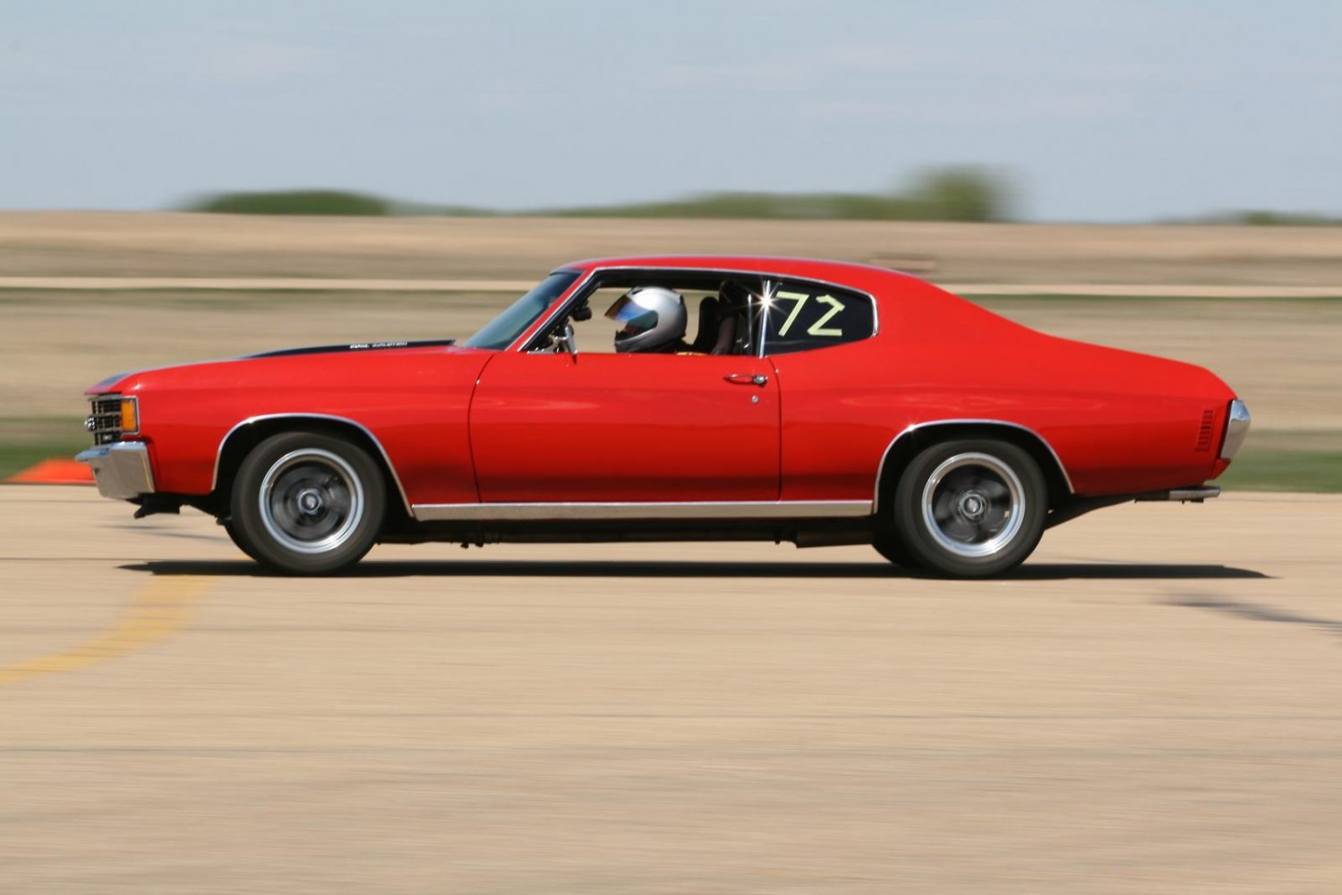 Red classic muscle car with sport coupe profile in motion