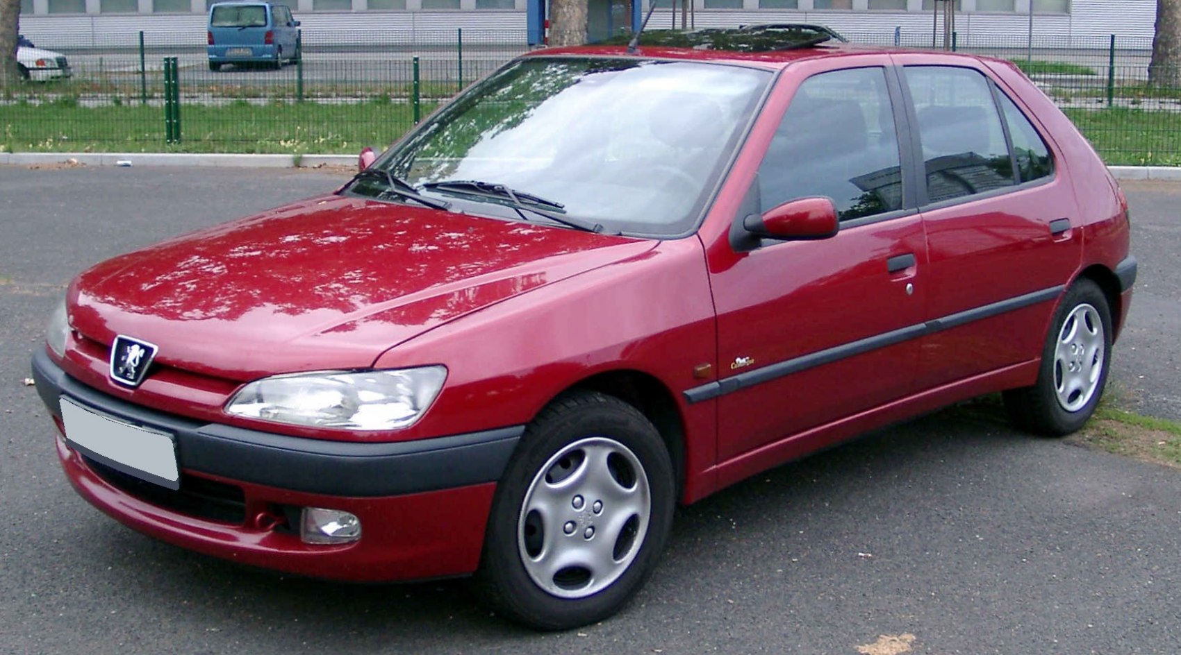 Front side profile of red hatchback with alloy wheels and headlights