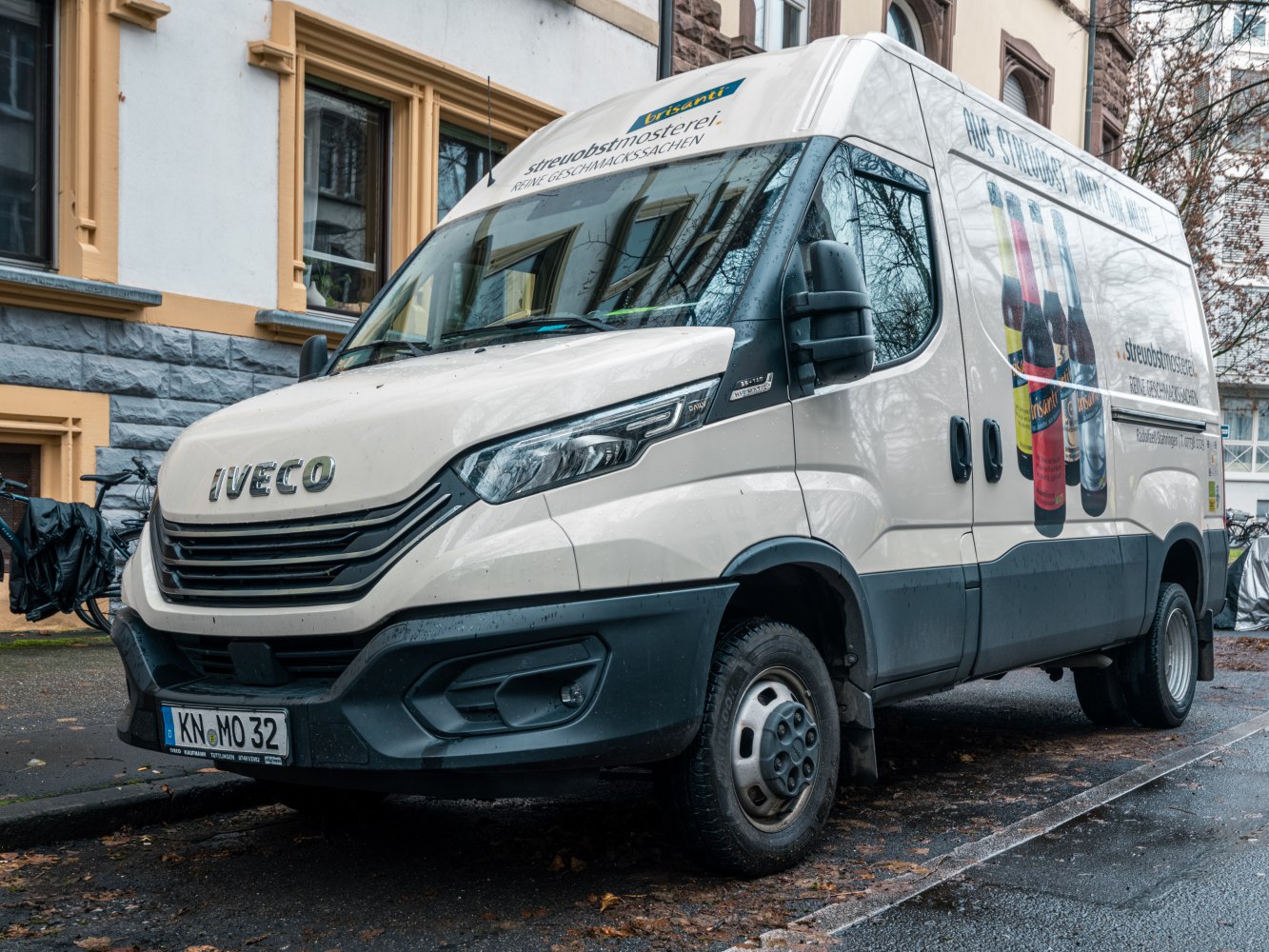 Front and side view of a facelifted panel van with beverage advertising.