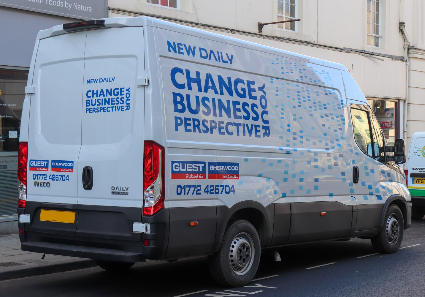 White panel van with blue business ads and pixel pattern graphics