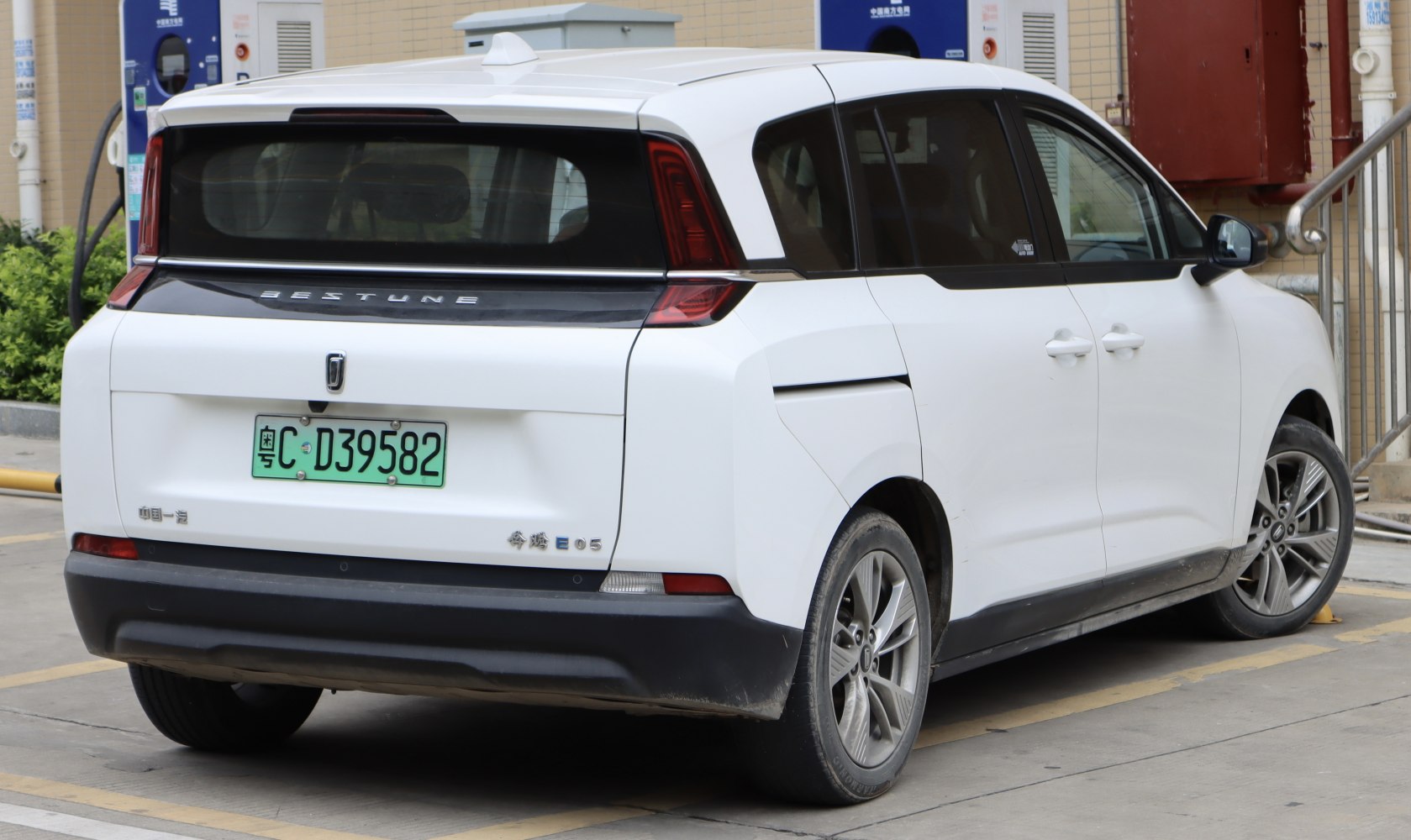 Rear view of white electric minivan with futuristic tail lights and window design