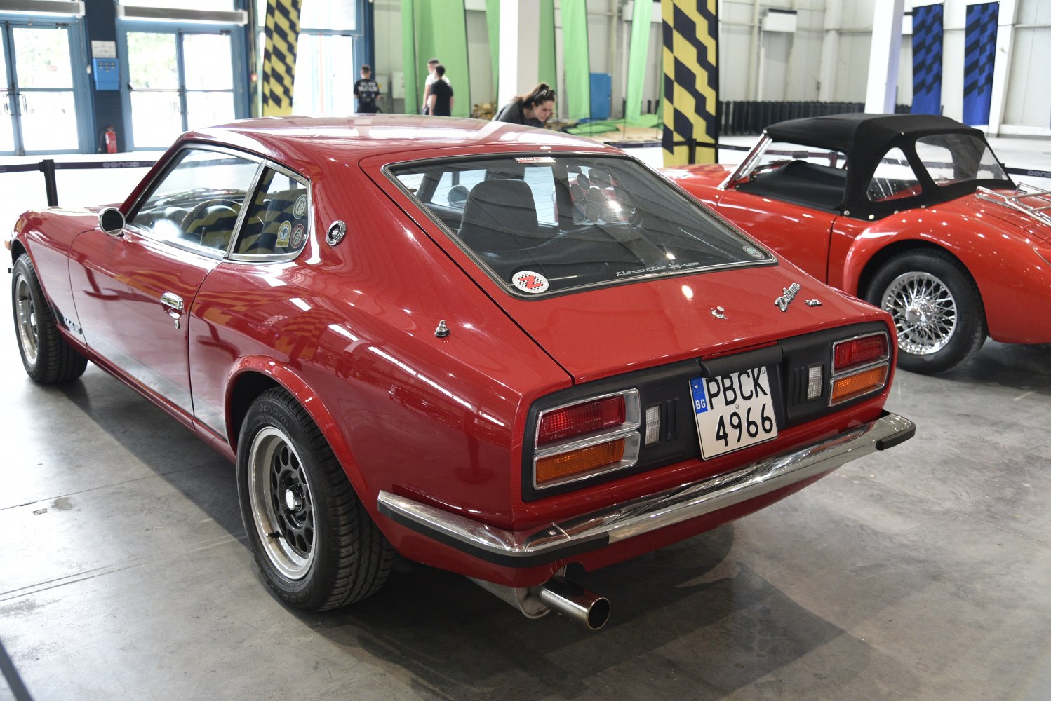 Rear side view of red vintage sports coupe with distinct taillights and 2+2 seating