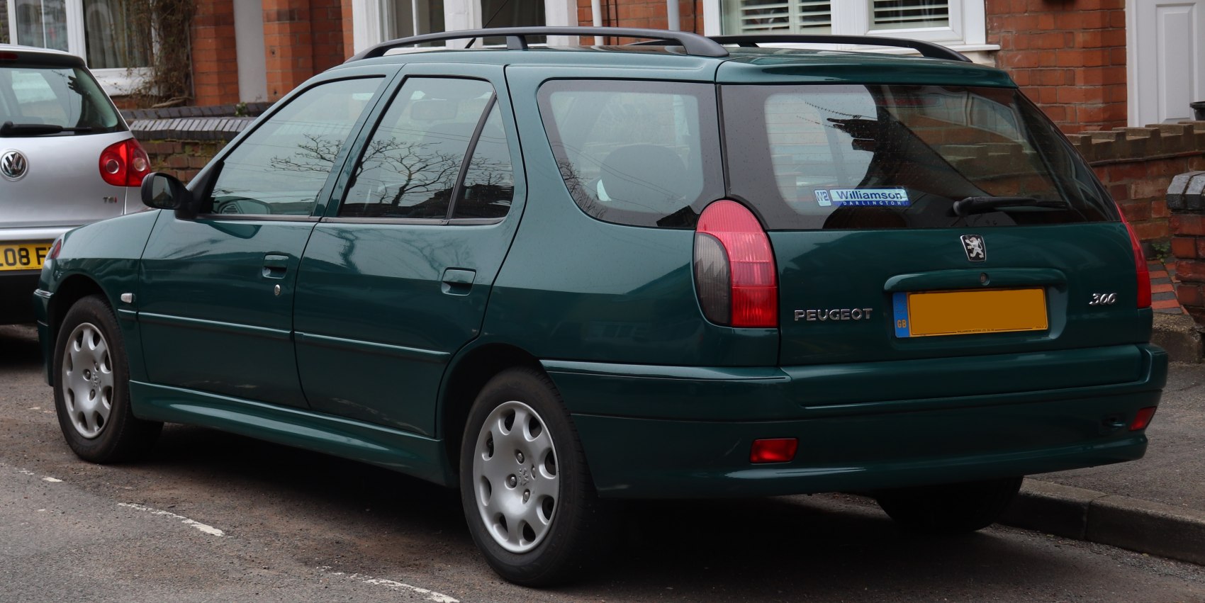 Rear side view of an estate car with roof rails and distinct rear lights.