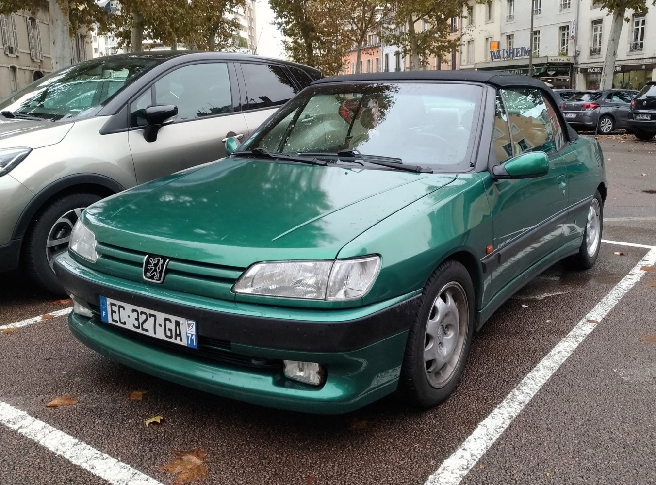 Green convertible with black soft top parked, front and side view