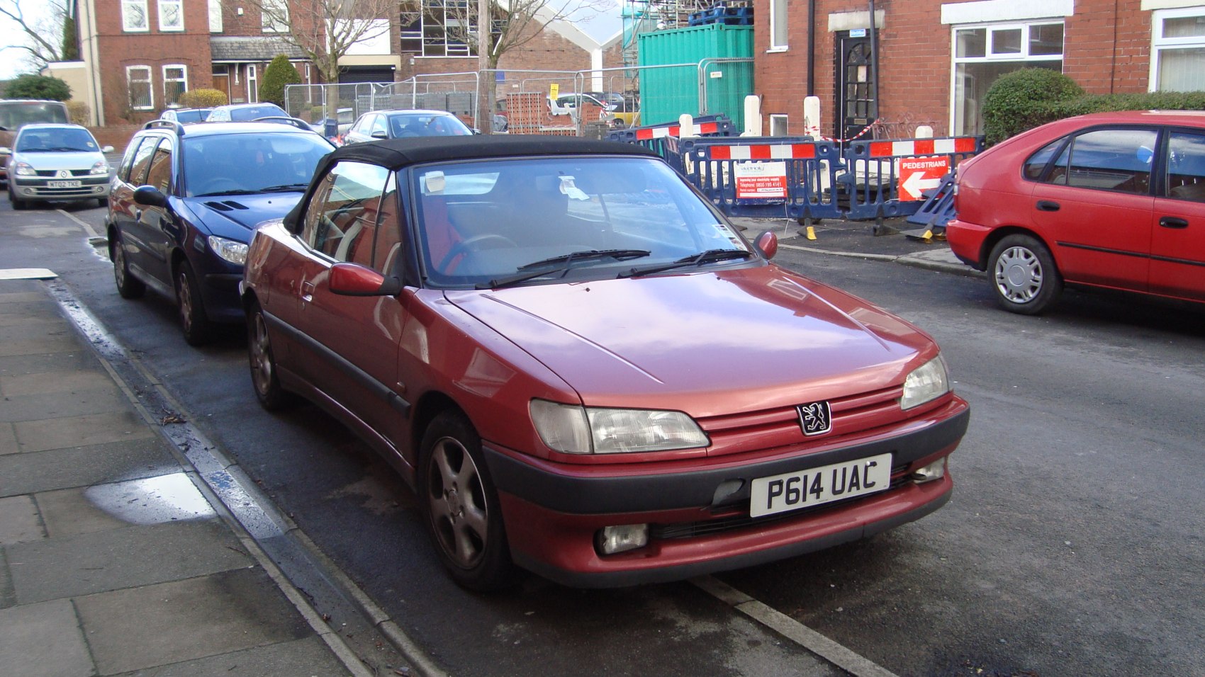 Red convertible with black soft top parked on street