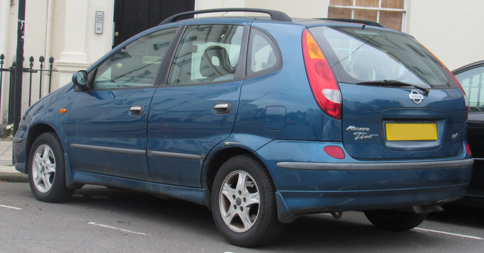 Rear-side view of blue compact MPV with roof rails and alloy wheels