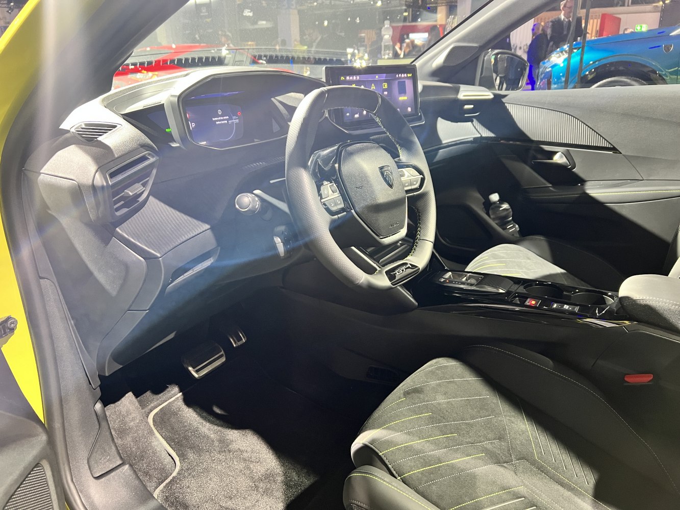 Compact steering wheel with digital instrument cluster and central touchscreen display.