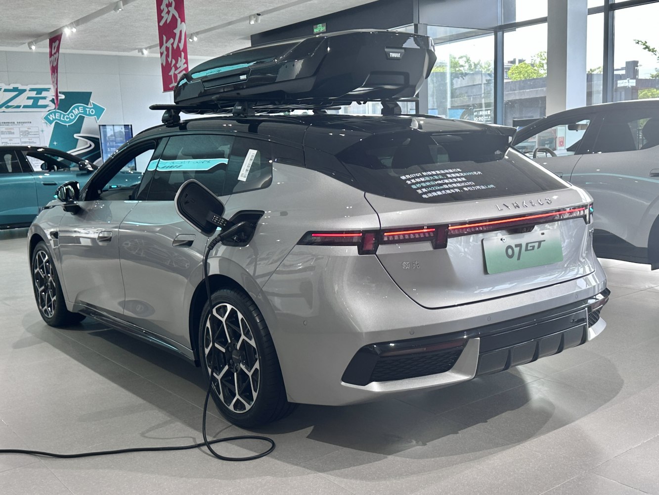 Electric SUV charging cable connected, roof cargo box mounted