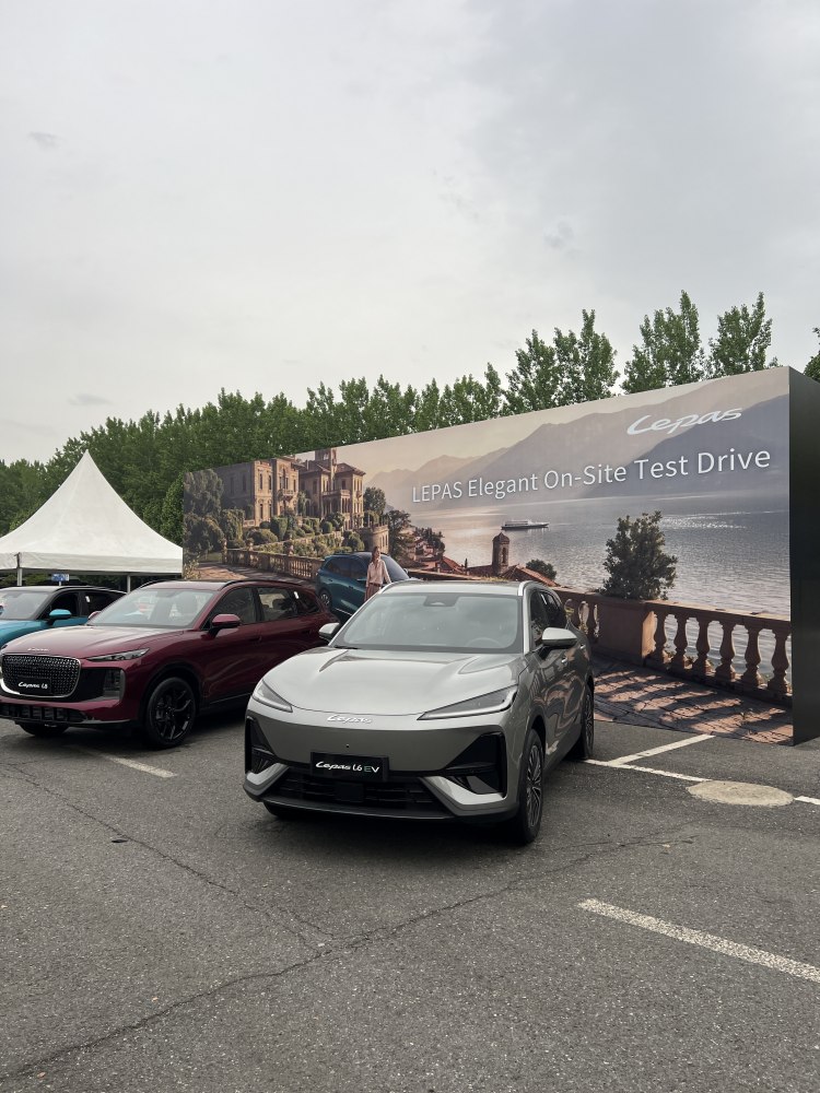 Sleek front view of an electric SUV in a parking lot with promotional backdrop