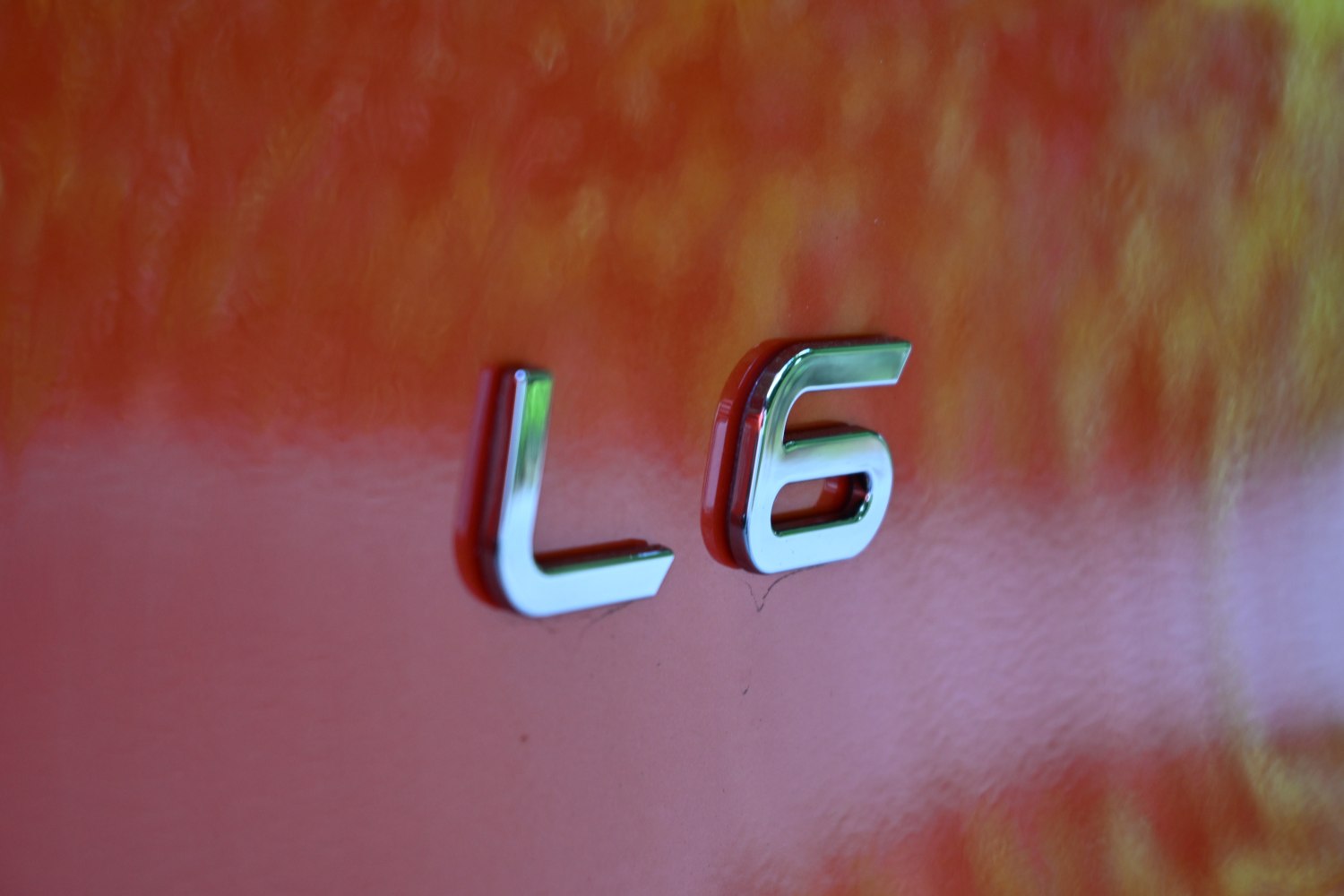 Close-up of chrome L6 badge on orange car surface