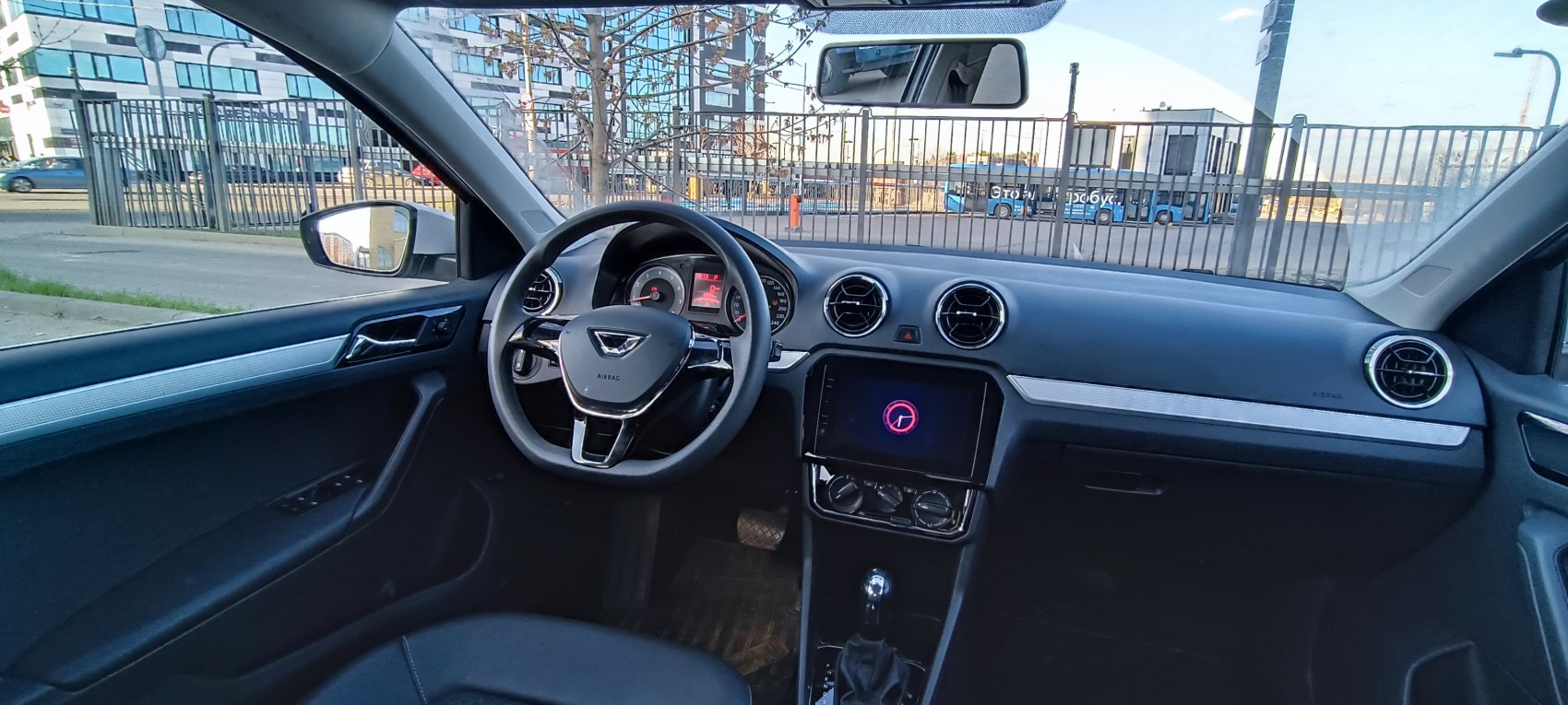 Steering wheel, round air vents, touchscreen, climate control knobs.