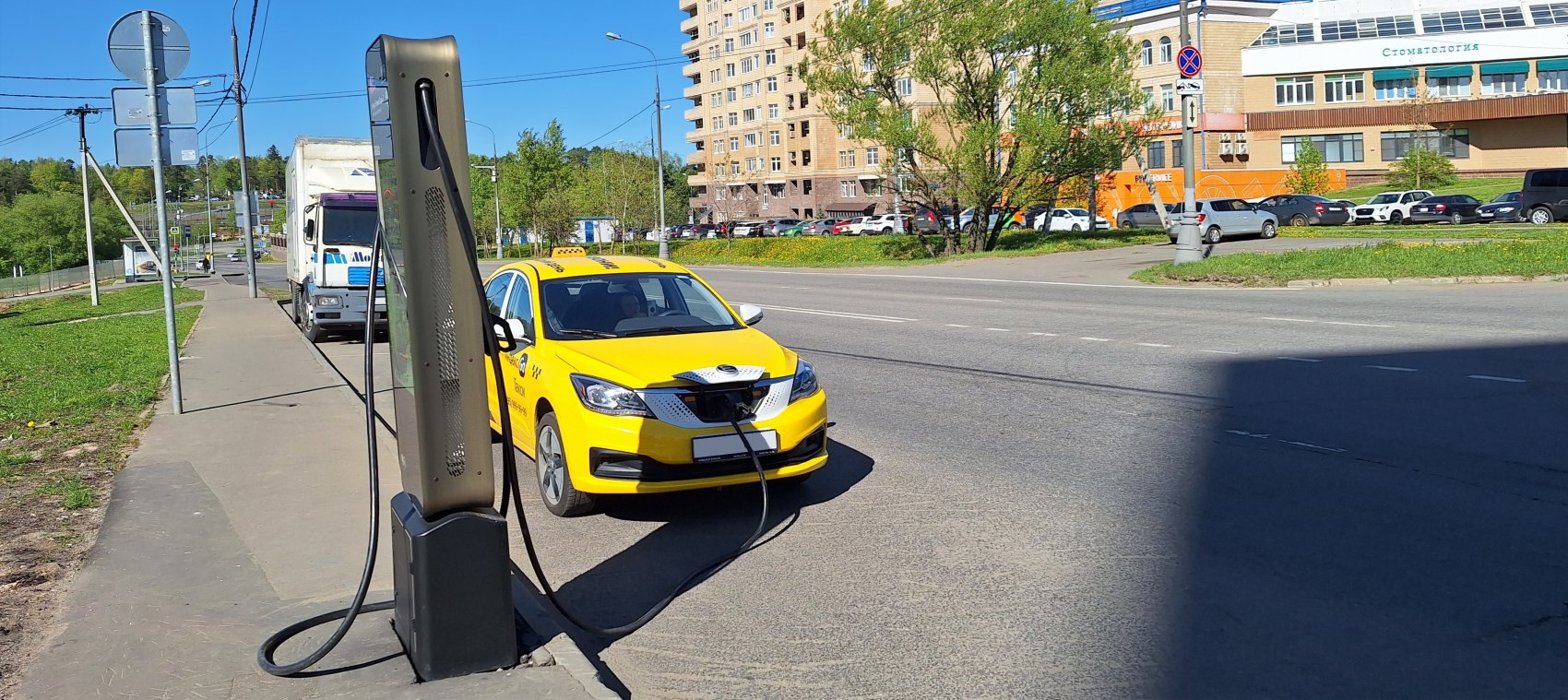 Yellow electric taxi charging at public roadside station