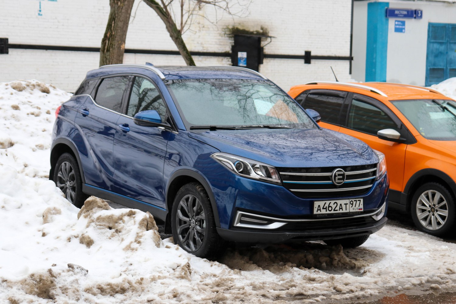 Blue SUV with sleek front grille and LED headlights parked in snowy urban setting