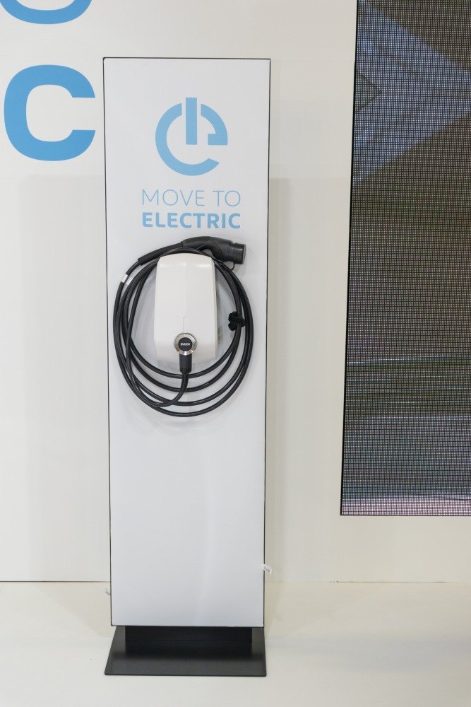 Wall-mounted electric vehicle charging station with coiled cable