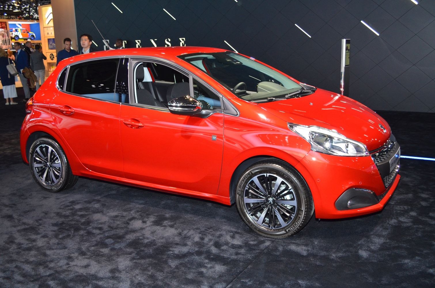 Red hatchback car side profile with alloy wheels