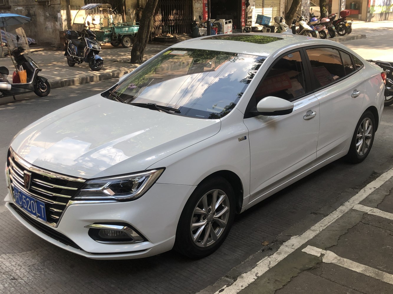 White mid-size sedan front-side view with sleek headlights and chrome grille