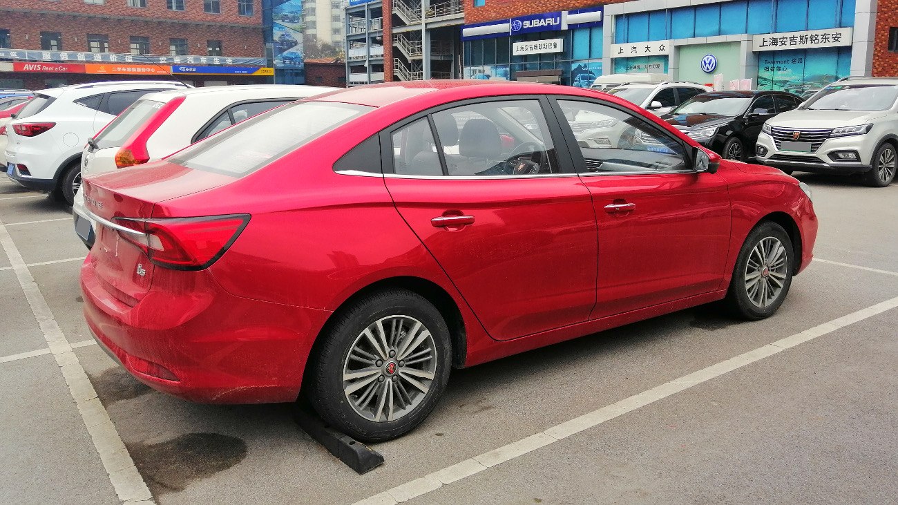Red sedan side profile featuring rear lights and alloy wheels
