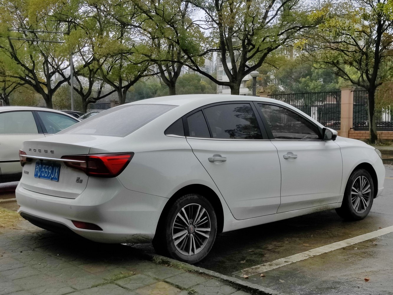 Rear and side view of white sedan with tinted windows and alloy wheels