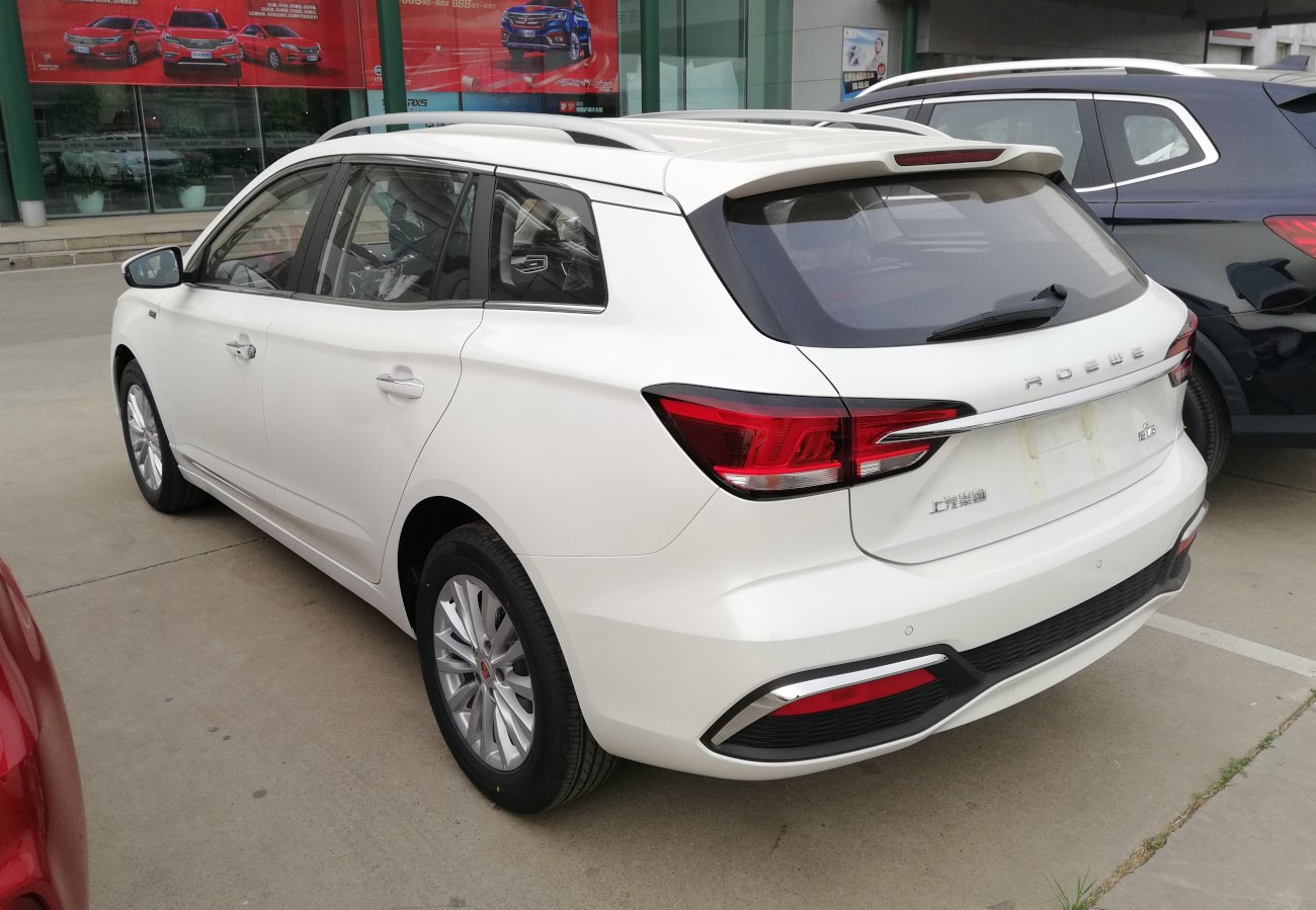 Rear and side view of a white wagon with roof rails and distinctive tail lights