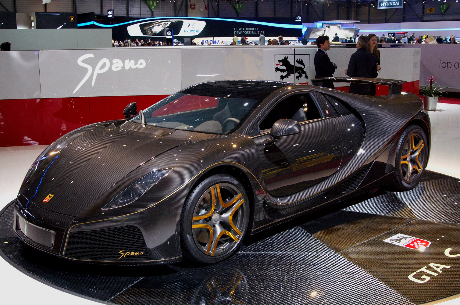 Carbon fiber body and orange accented wheels of a sleek supercar.
