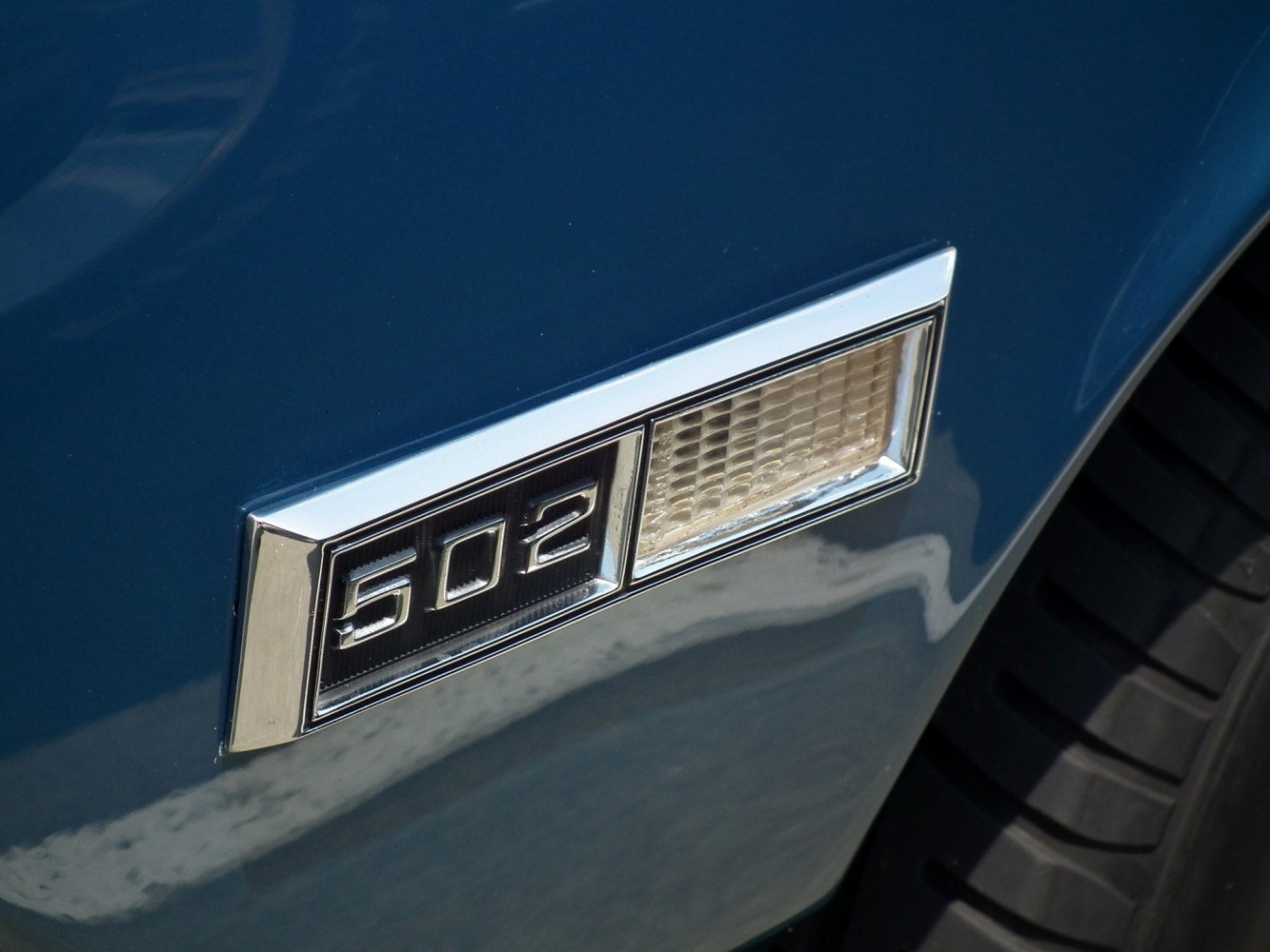 Close-up of 502 engine badge with adjacent light on blue surface