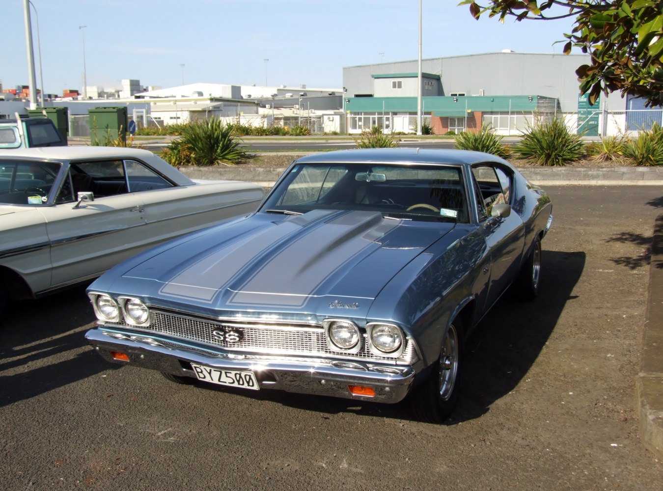 Dual headlights and pronounced hood scoop on a vintage muscle car front.