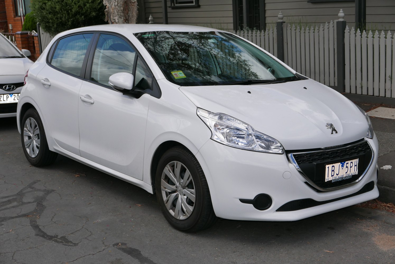 Front-three-quarter view of a white compact hatchback with distinctive headlights and grille.