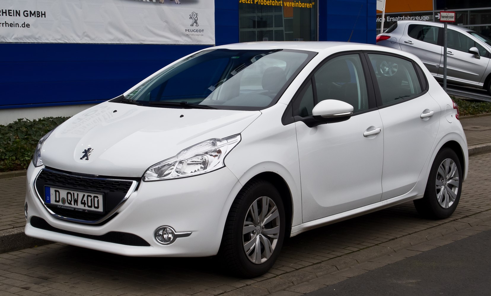 Front and side view of white hatchback with distinctive headlights and grille